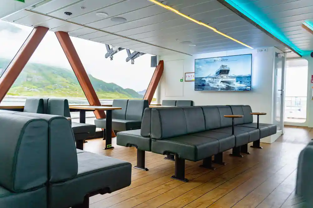 Boat interior with seating and large windows showing mountains