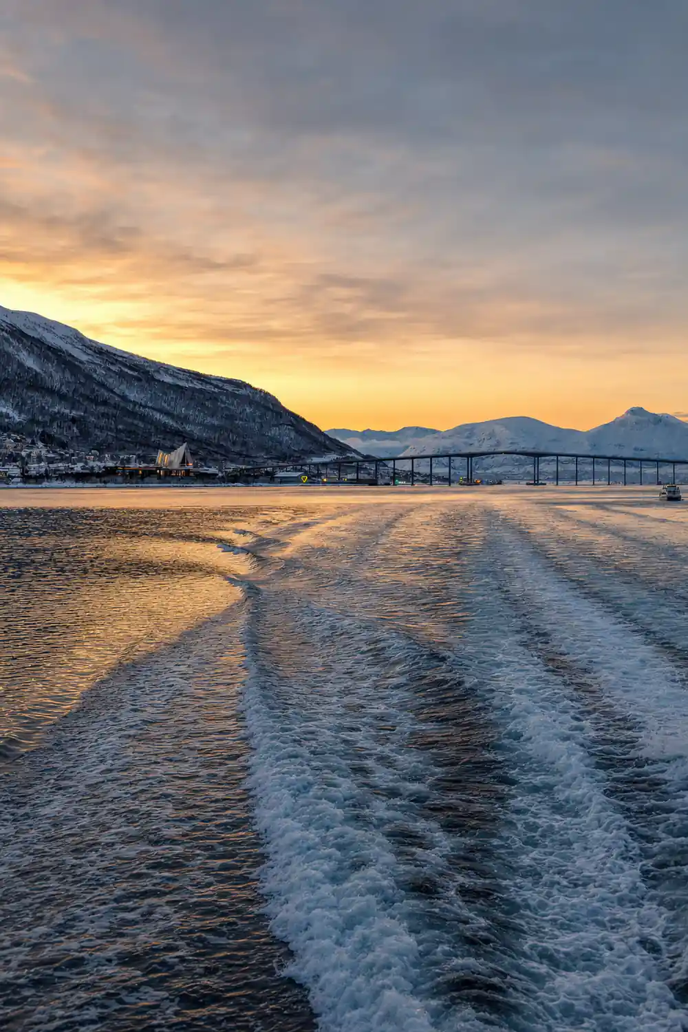 Frozen beach with bridge and snow-covered mountains