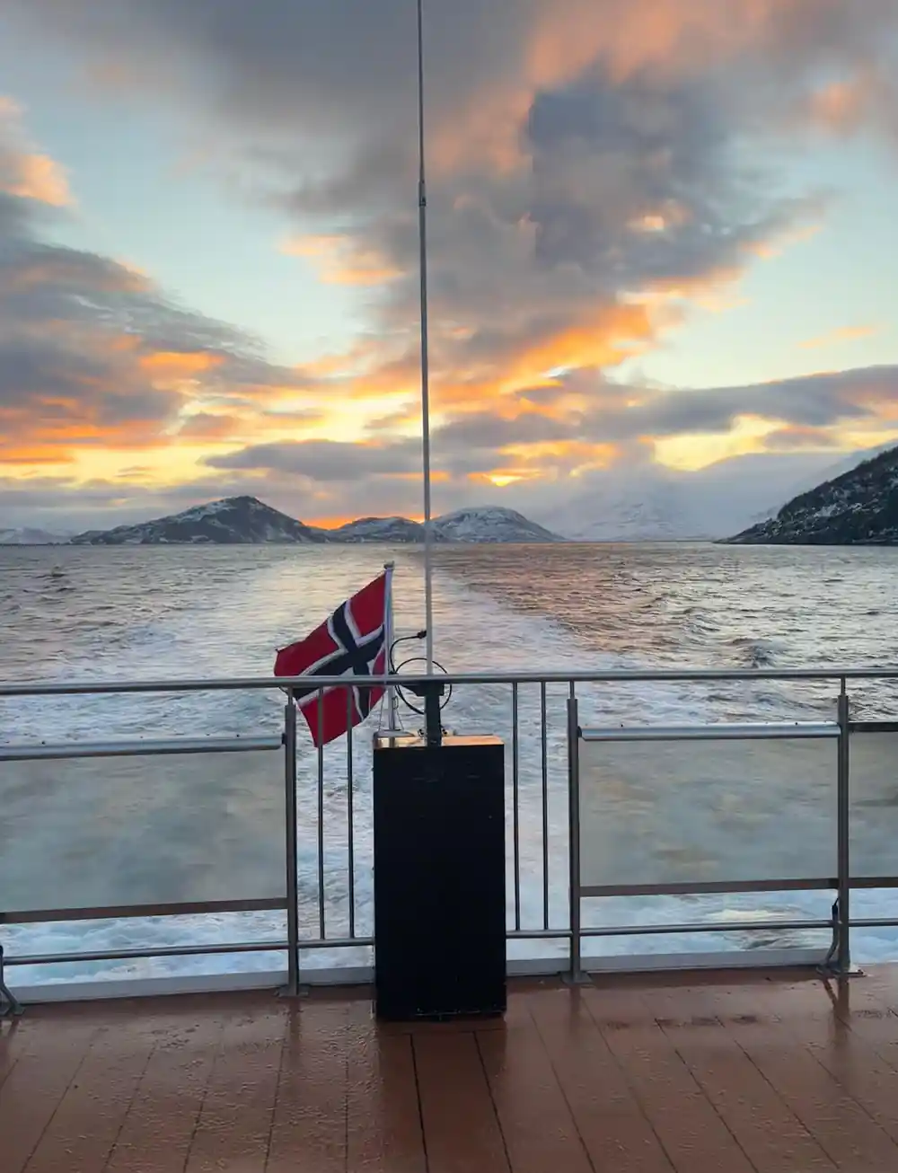 Norwegian flag on boat railing at dramatic sunset