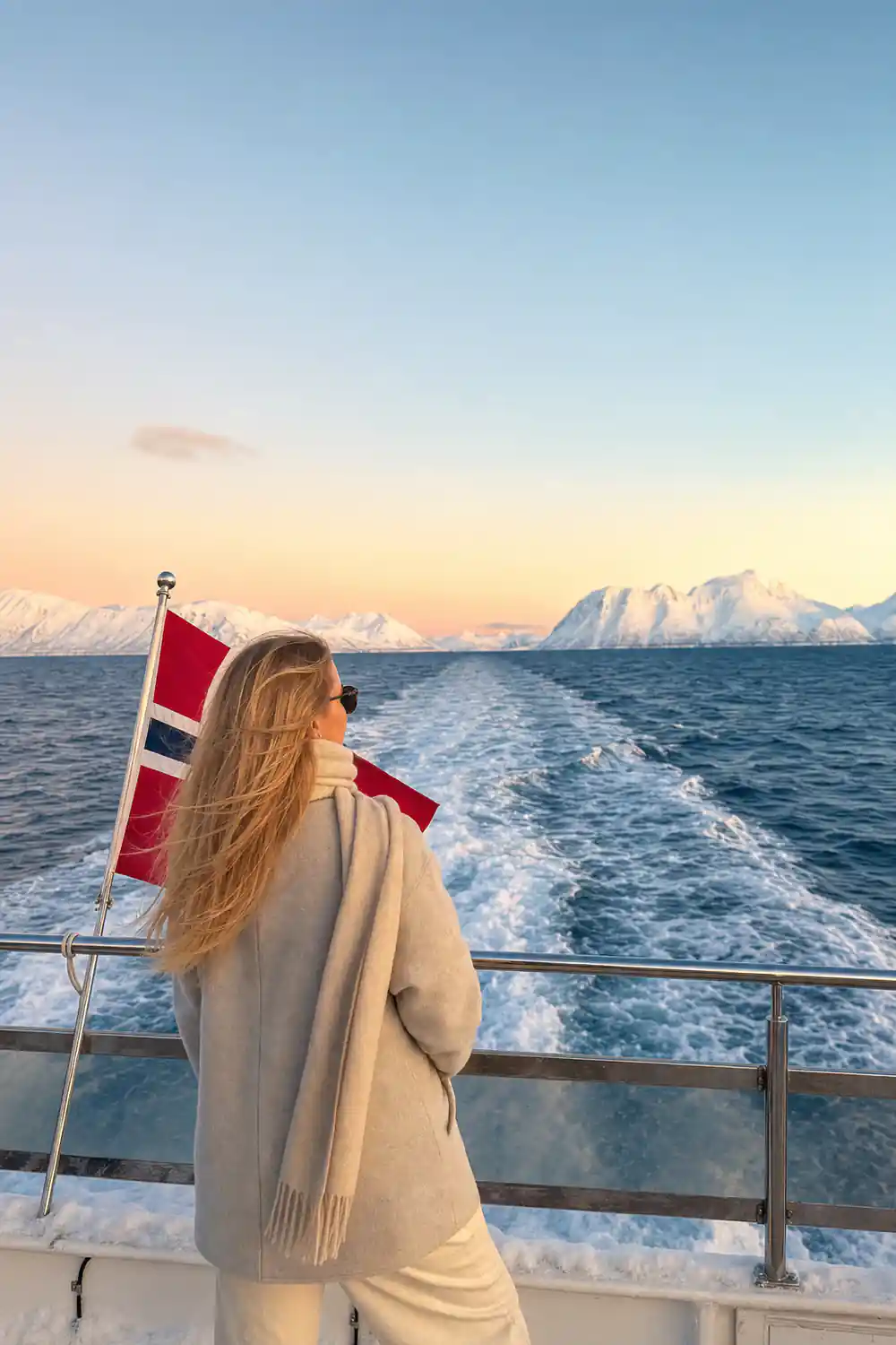 Norwegian flag on boat with snow-capped mountains
