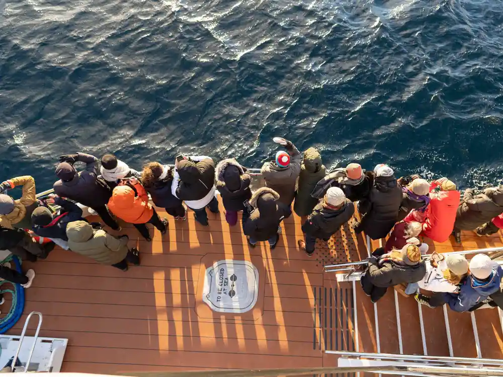 Overhead view of passengers on boat deck with ocean below