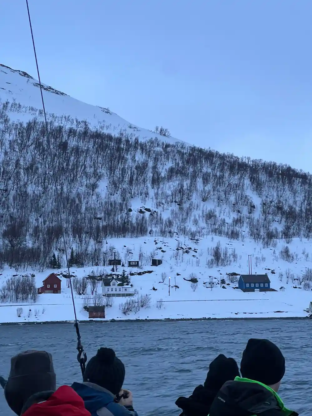 People in boat viewing snowy fjord village
