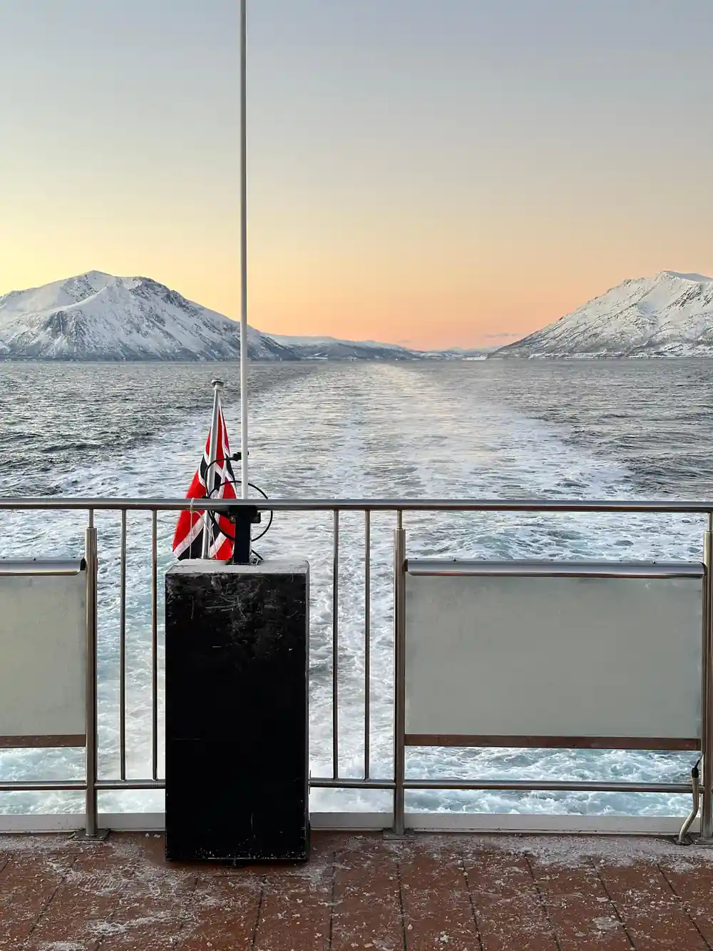 Red sailboat on deck with twin mountains at sunset