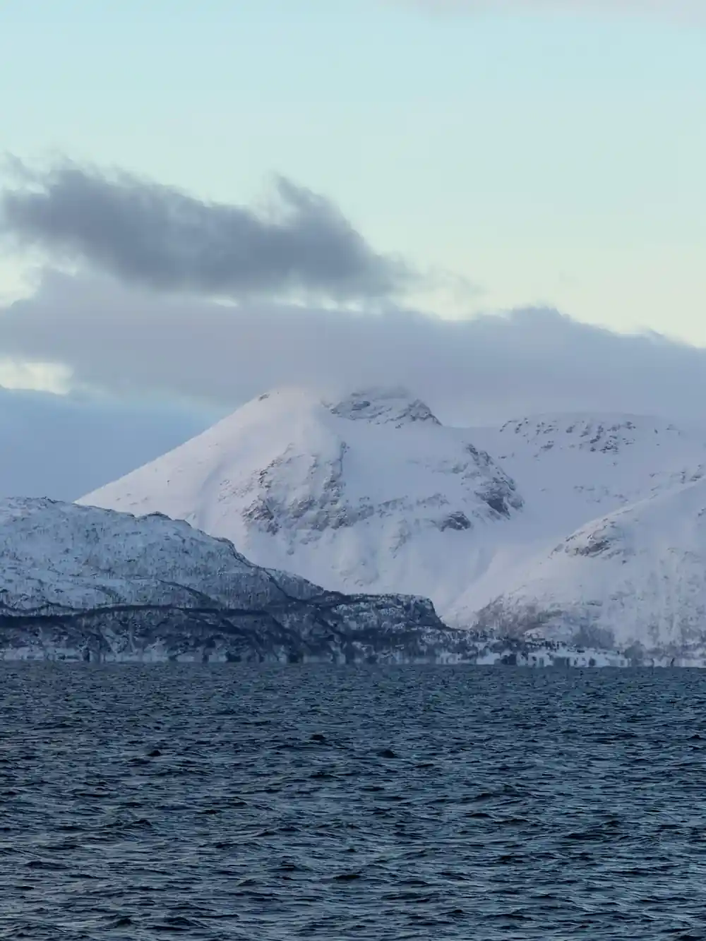 Snow-covered mountain peak rising from dark water