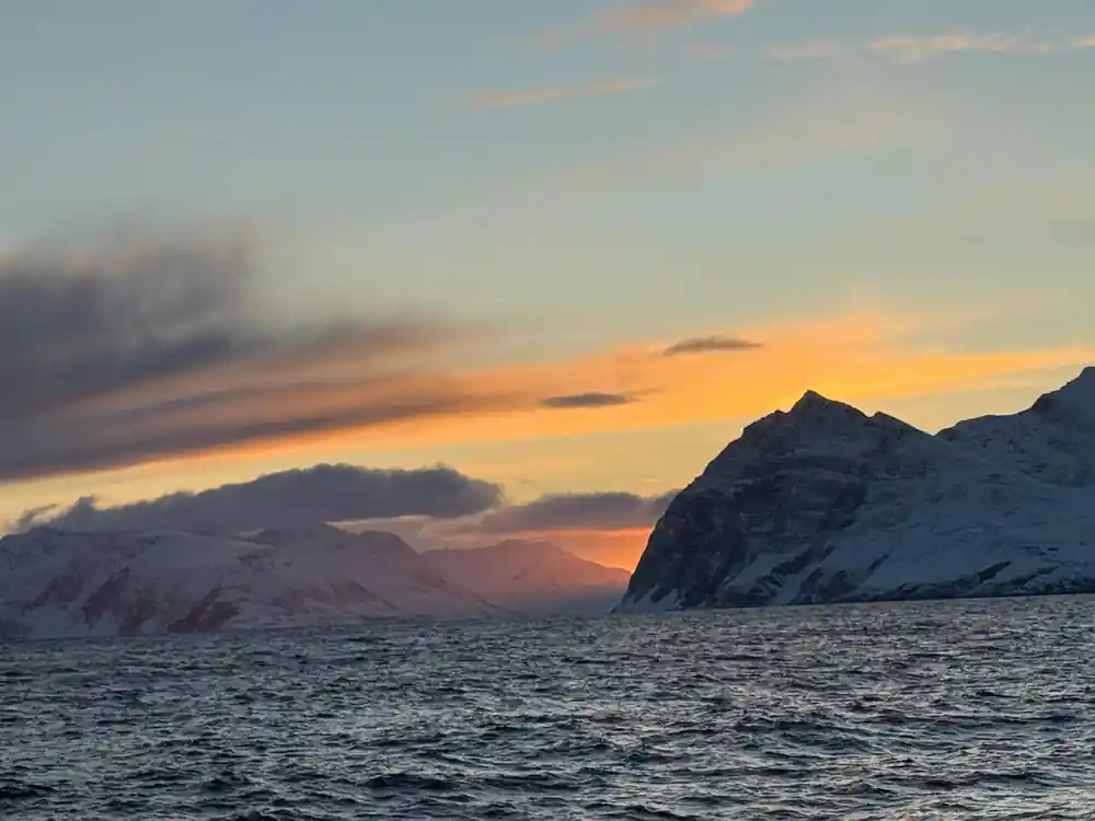 Snow-covered mountains at sunset over dark water