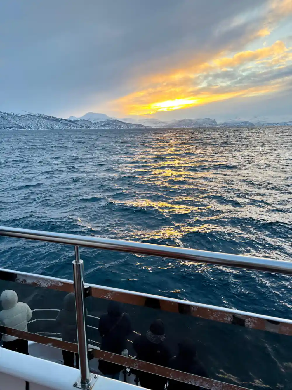 Sunset over ocean waves viewed from boat railing