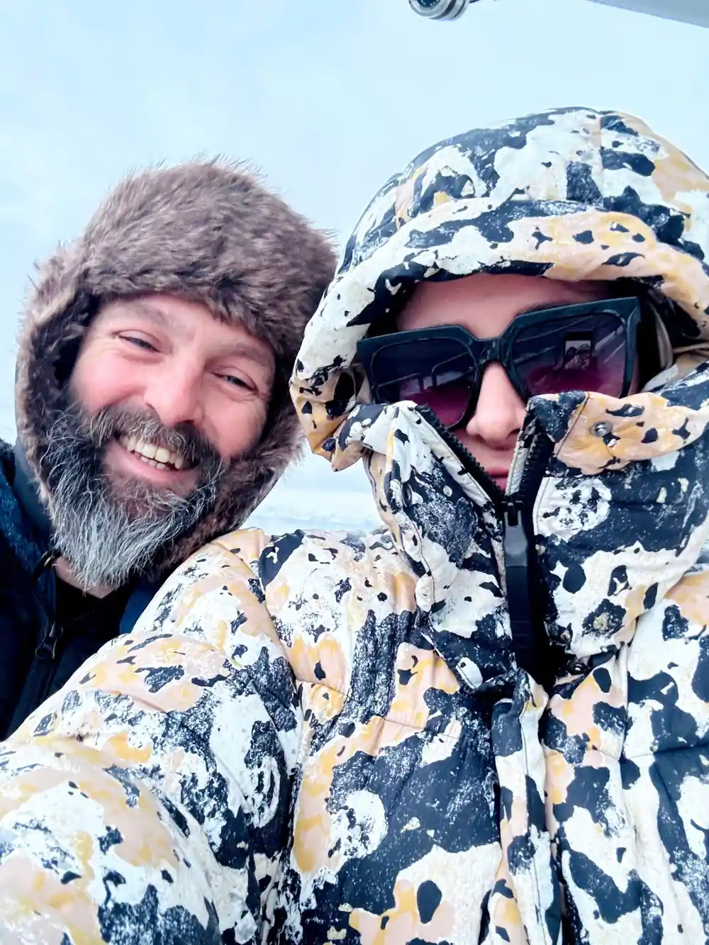 Two men in camouflage clothing smiling at camera