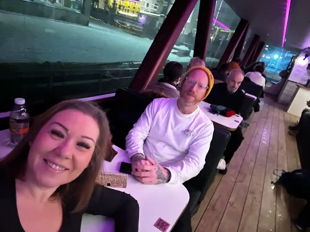 Two people sitting indoors at bar with purple lighting